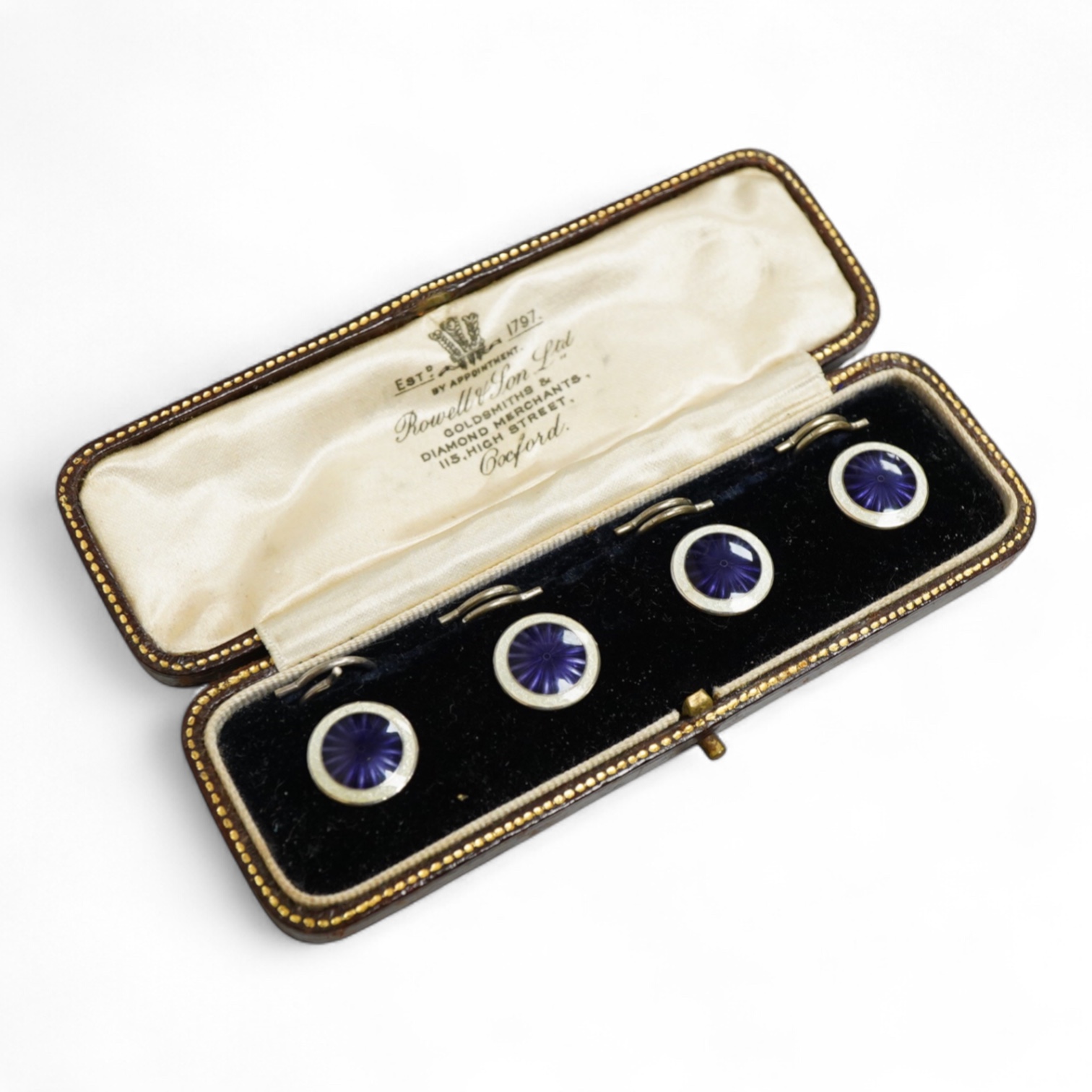 A set of four silver and two colour enamel buttons, by Lawson, Ward & Gammage Ltd, Birmingham, 1910, diameter 12mm, in original gilt tooled leather case by Rowell & Son Ltd of Oxford.